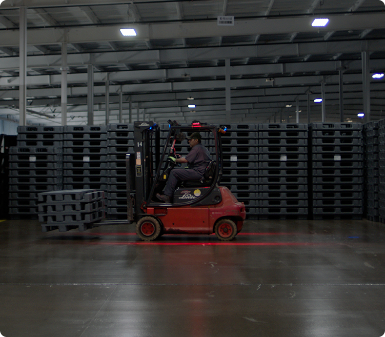 Forklift and stacked reusable pallets in a Shuert warehouse